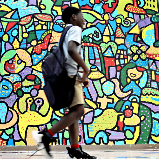 student in front of colorful mural